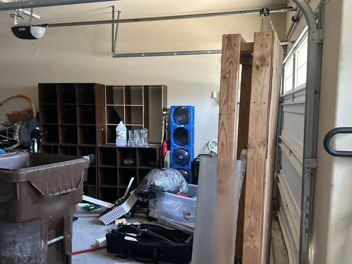 Before: cluttered two-car garage filled with furniture, boxes, and household items