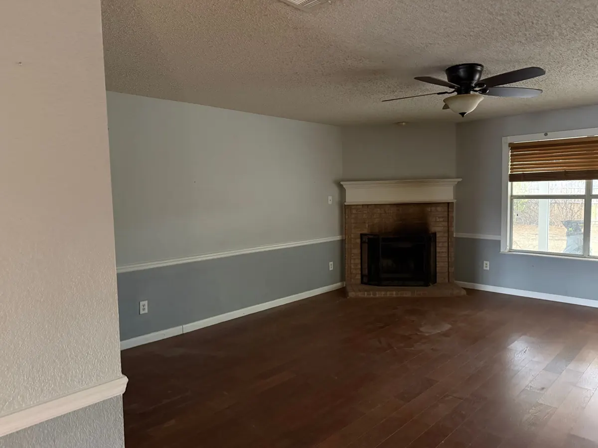 After: empty, swept living room with a corner fireplace after the Hot Mess Haulin crew cleared it